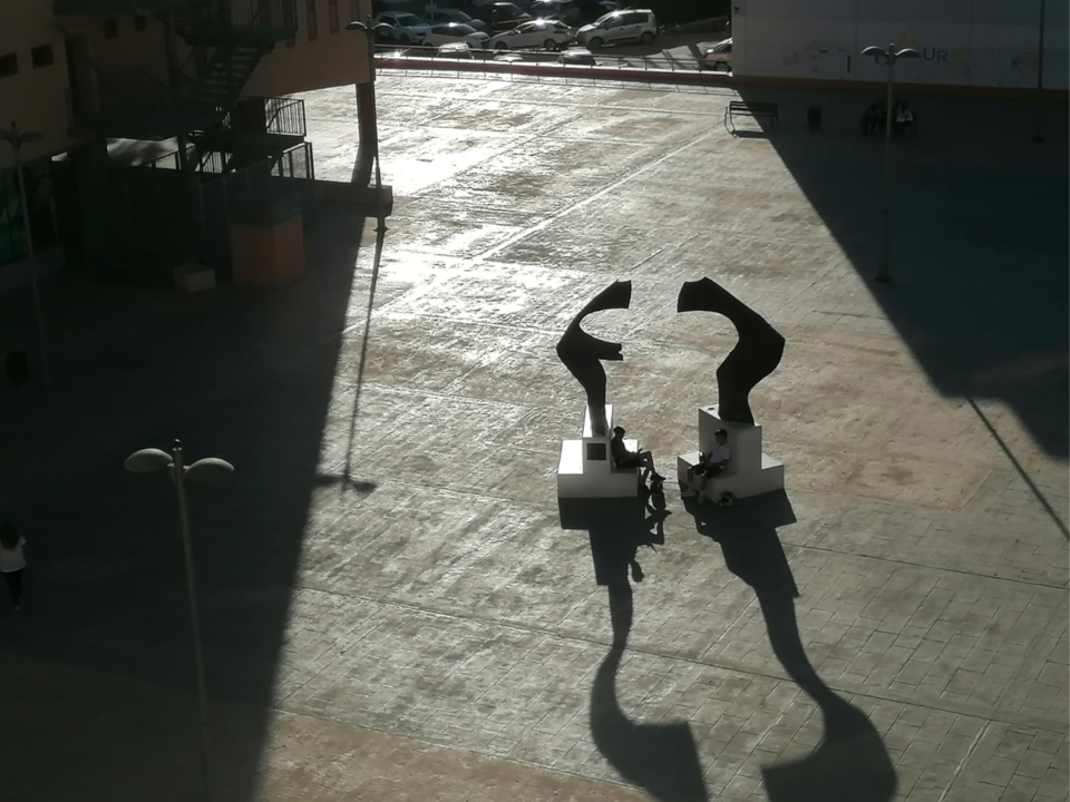 La sombra espesa de la tarde en un pueblo del Levante español, con plaza enlosetada.