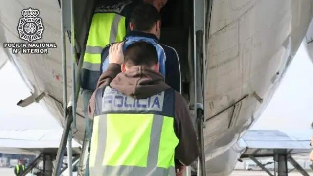 Agentes de policía embarcan a varias personas migrantes en un vuelo de deportación - Foto de la Policía